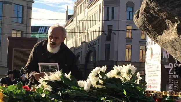 A man stands over flowers at the base of a memorial for victims of Soviet-era political repression