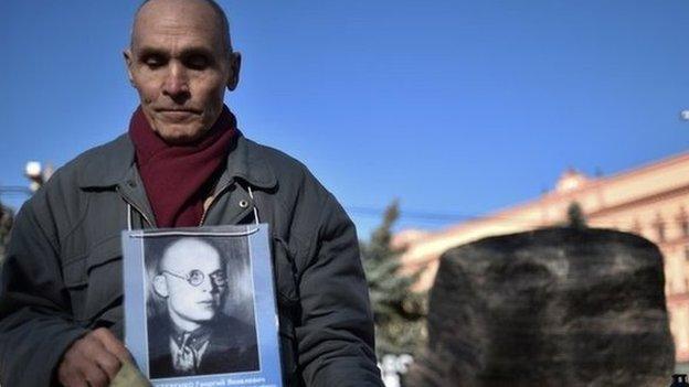 A man holds his father's portrait near the memorial to the victims of Soviet-era political repression, the Solovky Stone monument, on Lubyanka Square in Moscow, on October 29, 2014