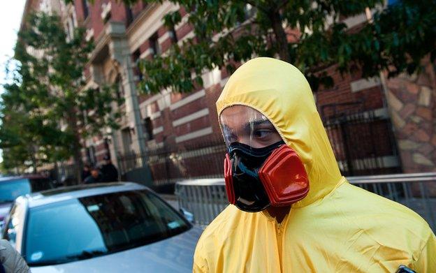 A man, dressed in a biohazard costume, stands on the corner of 546 West 147th Street in New York City