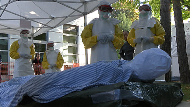 Volunteers look on at a dummy patient on a training course