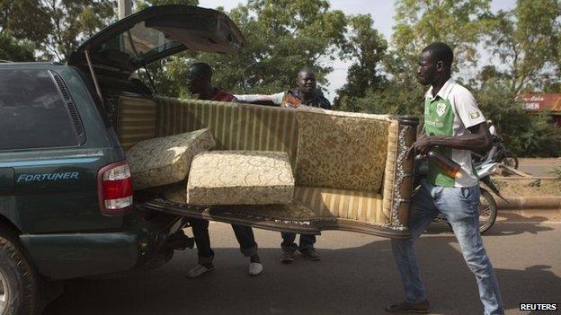 People carry a couch looted from the house belonging to Francois, younger brother of Burkina Faso's ex-President Blaise Compaore, in Ouagadougou, capital of Burkina Faso, 31 October 2014
