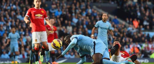 Yaya Toure goes down under a challenge from Marcos Rojo