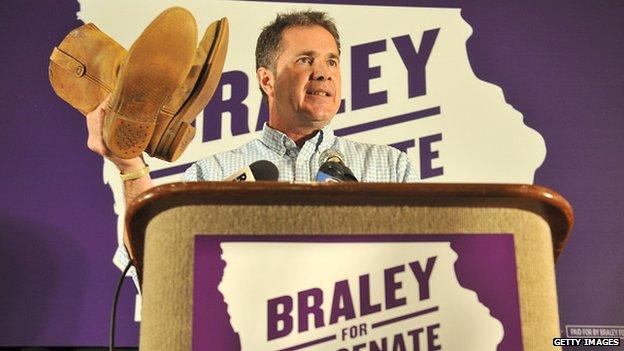 Bruce Braley holds up work boots