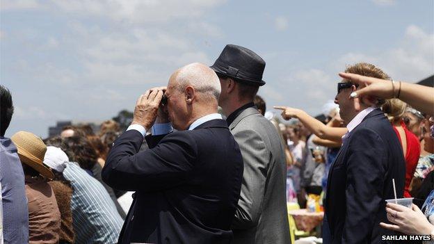 Man with binoculars watching racing