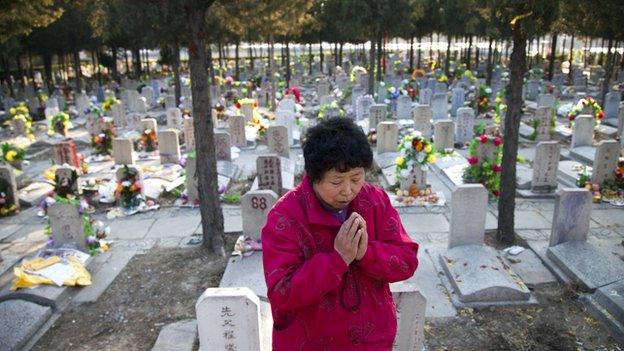 This photo taken on April 4, 2011 shows a Chinese woman praying at the grave of a loved one at the Babaoshan cemetery in Beijing