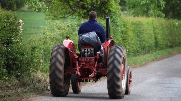 A famer drives his tractor down a country lane in rural Shropshire