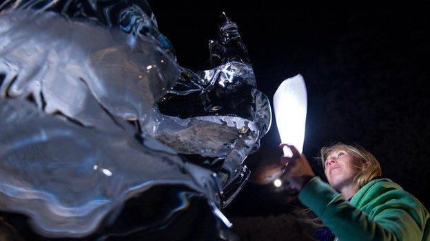 Emma Craig from Chwarae Teg holding a torch up to the statue in the middle of the night