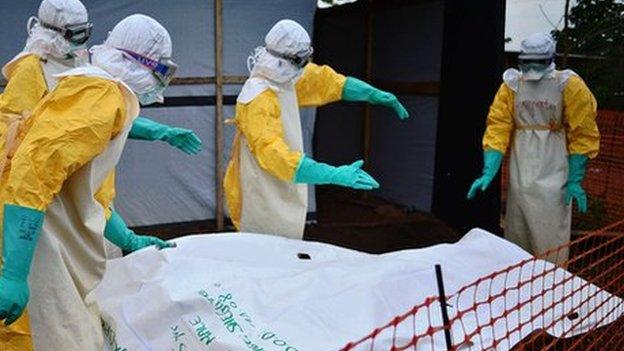 Health workers from Medecins Sans Frontieres disinfect body bag in Sierra Leone, August 2014