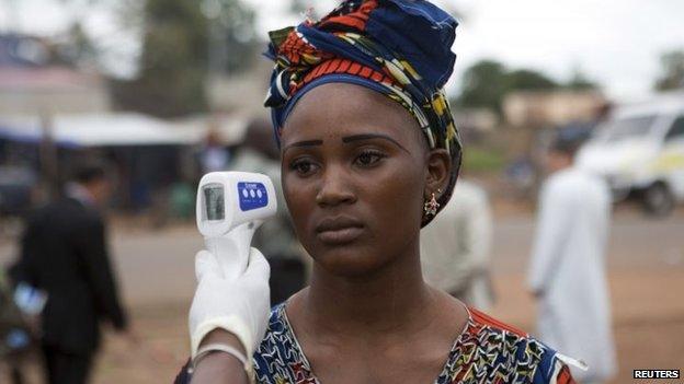 A health worker checks the temperature of a woman entering Mali from Guinea at the border in Kouremale 2 October 2014