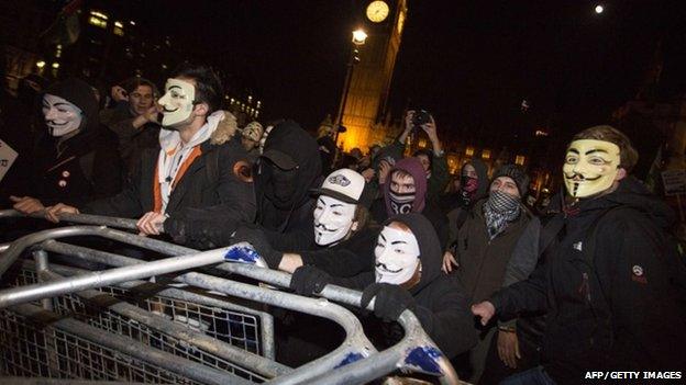 Anti-capitalist protesters wearing Guy Fawkes masks remove police barricades during the "Million Masks March" in Parliament Square