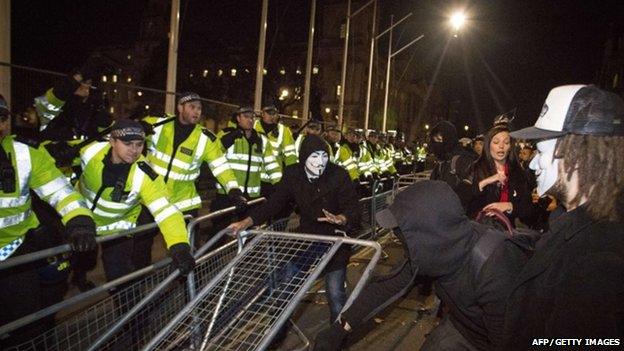 Protesters wearing Guy Fawkes masks clash with police