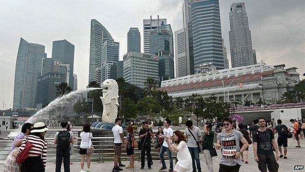 Tourists take photographs at the Merlion Park in Singapore on 15 October 2014