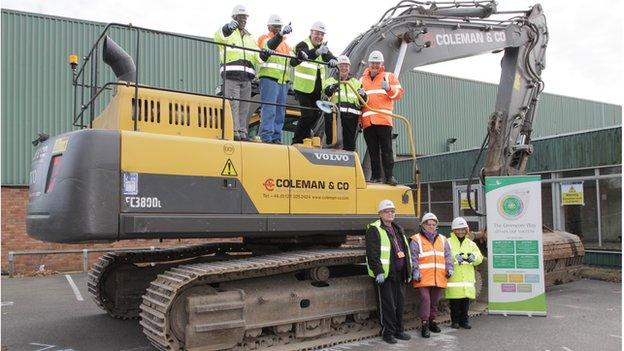 Greencore workers standing on and in front of a digger