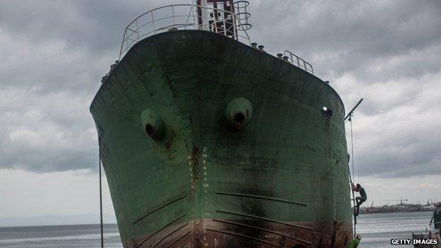 Workers from a salvage crew prepare a large ship to be rolled back to sea in the coastal area renamed by residents ' Yolanda Village' on August 13, 2014 in Tacloban, Leyte, Philippines