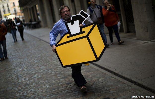 Businessman Emilio Busquets carries a drawing of a ballot box to decorate his shop ahead of voting on an informal poll, scheduled for next Sunday, in Girona, Spain, on Saturday Nov.8, 2014