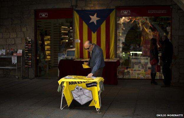 A man looks at information on a table about an informal poll scheduled for next Sunday in a street in Girona, Spain, on Saturday Nov. 8, 2014