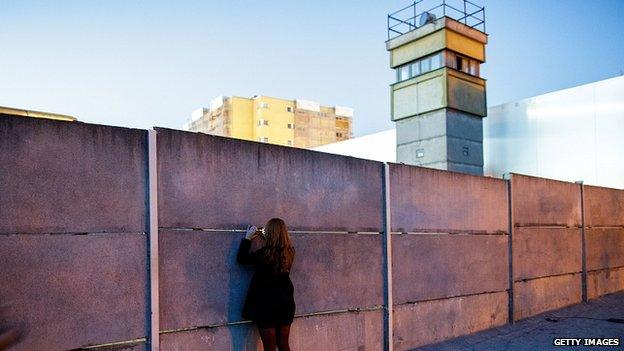 A visitor peeks into the former "death strip" between layers of the former Berlin Wall next to a former East German guard tower at the Berlin Wall Memorial at Bernauer Strasse. 8 Nov 2014