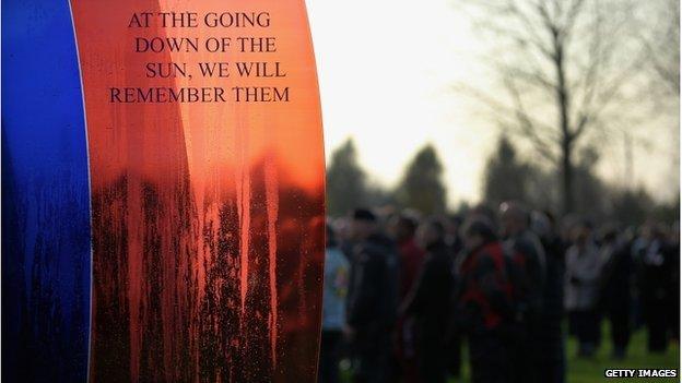 A crowd stands near a memorial