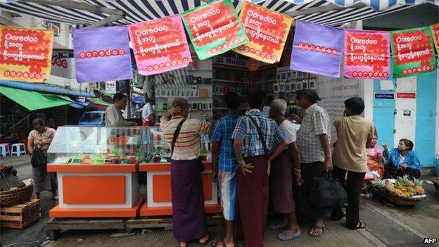 This photo taken on 1 August 2014 shows people buying Ooredoo mobile phone SIM cards from a shop in Yangon.