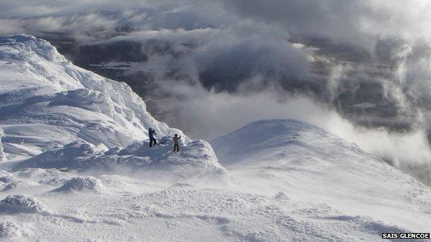 Two walkers take in the view from the summit of Meall a Bhuiridh in Glencoe this winter