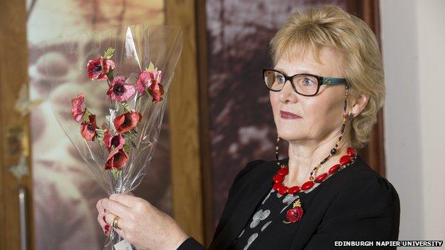 Catherine Walker holds the poppy sculpture aloft