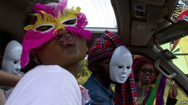 People wearing masks pose as they sit in a vehicle during the first Ugandan gay pride rally since the overturning of a tough anti-homosexuality law, which authorities have appealed, in Entebbe, on 9 August 2014