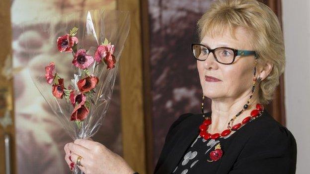 Catherine Walker holds the poppy sculpture aloft