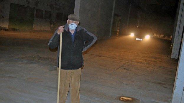 A volunteer with broom, lit by a car's headlights