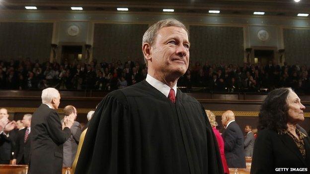 Supreme Court Chief Justice John Roberts stands at the 2014 State of the Union address.