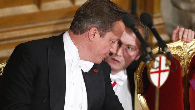 David Cameron listens to an aide