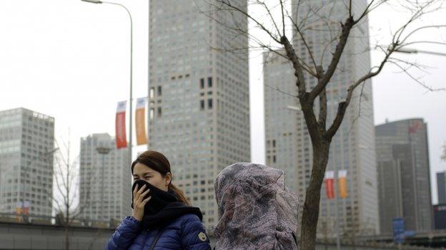 Chinese women cover their face with scarf as they walk past the Central Business District in Beijing, China Tuesday, Nov. 11, 2014