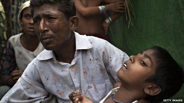 Roshida Moud, 12, is held by his father as he explains that his son was hit in the head with a stone during the Rakhine violence