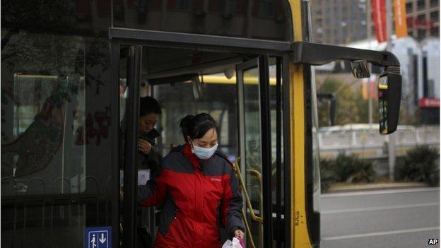 A woman wearing a mask walks out from a bus at the Central Business District in Beijing, China Tuesday, Nov. 11, 2014.