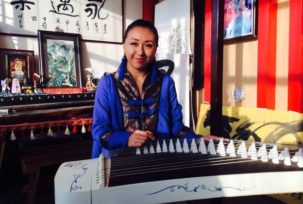 Screengrab of a woman playing the zither at the Han Dress Association meeting