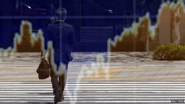 Man reflected in an electronic board outside a brokerage in Tokyo