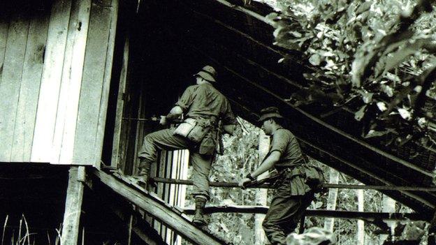 Carrying out a search of a wooden hut in the jungle