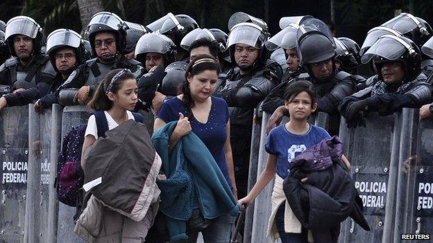 Passengers walk past police officers at Acapulco airport on 10 November, 2014.