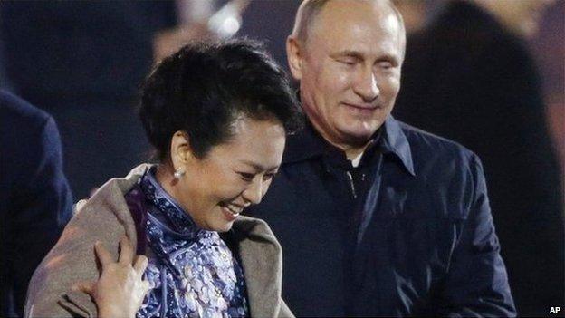 Russia"s President Vladimir Putin, right, puts a shawl on Peng Liyuan, left, wife of Chinese President Xi Jinping