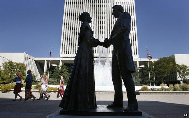 A file photo shows women walk past a statue of Joseph and Emma Smith outside the church office building for The Church of Jesus Christ of Latter-day Saints in Salt Lake City, Utah, in 2012