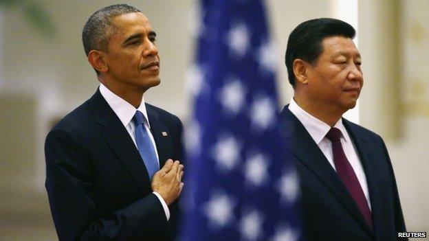 US President Barack Obama (L) and China's President Xi Jinping listen to national anthems behind a US flag during a welcoming ceremony at the Great Hall of the People in Beijing, 12 November 2014