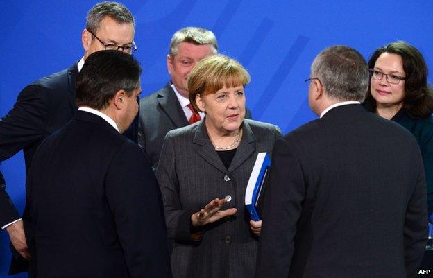 Angela Merkel, surrounded by cabinet ministers, is handed a report by Germany's council of economic advisers (12 Nov)