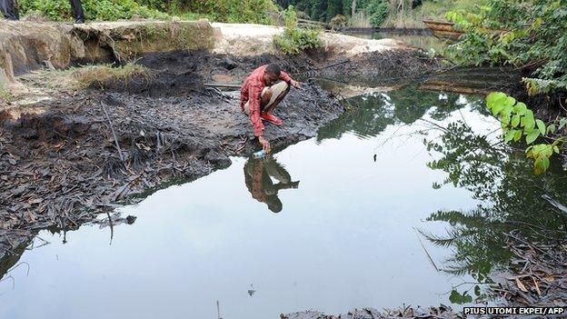 A man scoops spilled crude oil allegedly caused by Shell equipment failure floating at the bank of B-Dere waterways in Ogoniland, Rivers State, on August 11, 2011