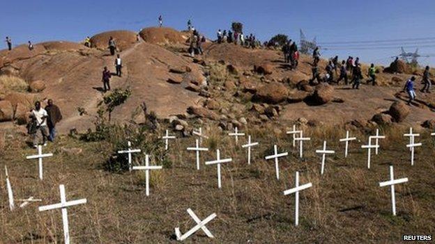 People walk near crosses placed at the site where 34 miners were killed in South Africa (14 May 2013)