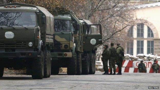 Armed people and military trucks are seen near a checkpoint outside a building on the territory controlled by the self-proclaimed Donetsk People's Republic in Donetsk,