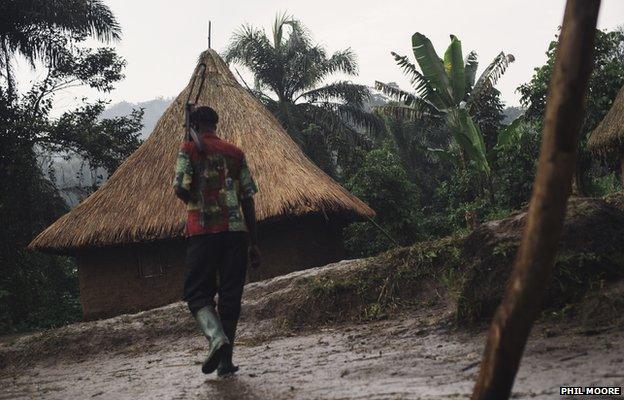 A militia man of an armed group carries an AK-47 in the village of Kalungu II