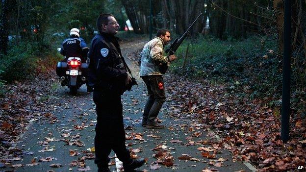 Police with tranquilizer gun walk through a wood in Montevrain, east of Paris. 13 Nov 2014