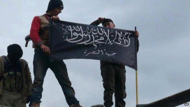 Rebels from the al-Nusra Front wave their brigade flag as they step on the top of a Syrian air force helicopter at Taftanaz air base in northern Syria on 2 November 2014