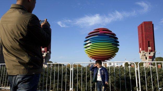 A child poses for photos near a logo for the Asia-Pacific Economic Cooperation summit in Beijing, China on 9 November, 2014