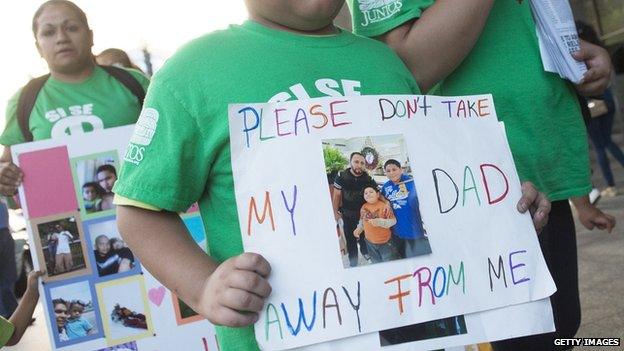 A child immigration reform protestor holds up a sign reading "please don't take my dad away from me".