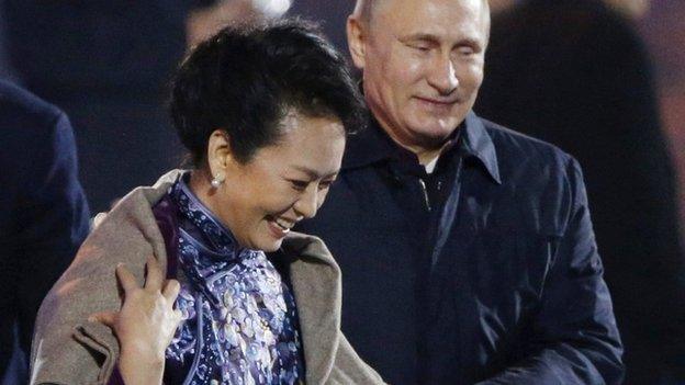 Vladimir Putin puts a shawl on Peng Liyuan, wife of Chinese President Xi Jinping